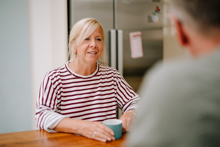 lady drinking a hot drink talking to gentleman at a table