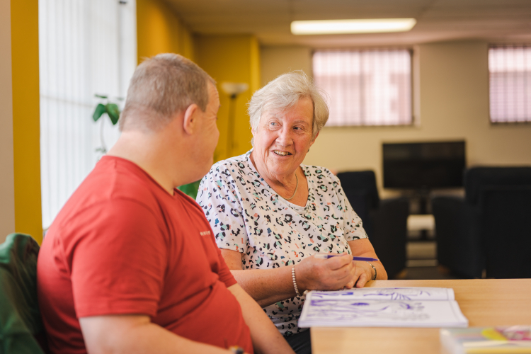 Elderly lady and younger male sitting at a table