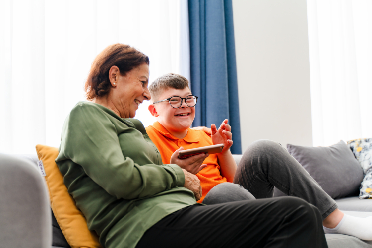 Little boy with down syndrome enjoy spending time with mother and watching mobile phone